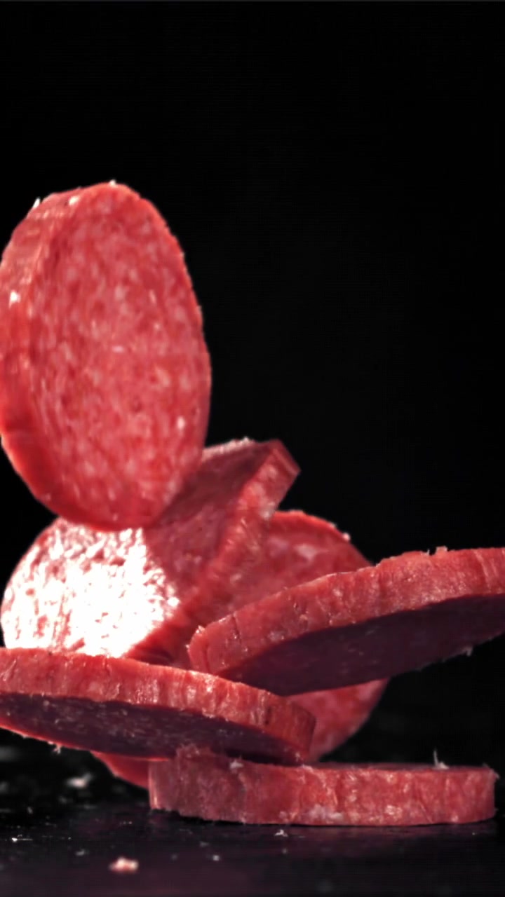 Fette di salame che cadono al rallentatore su sfondo nero