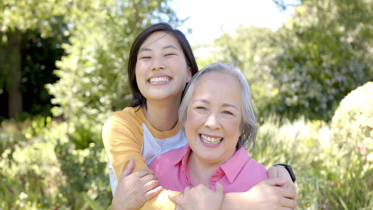 Smiling women hugging each other outdoors, enjoying time together in garden