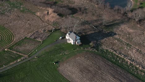 Lone-homestead-surrounded-by-rural-farmland-during-sunset-light-creating-shadow