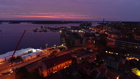 aerial trucking shot of cranes at port in slottsholmen city during purple sunset in sweden