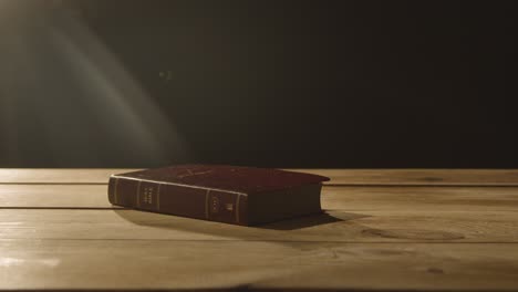 toma de concepto religioso de la vieja biblia sobre una mesa de madera en un charco de luz