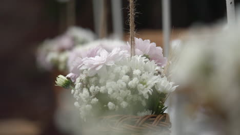 row of bouquet flowers hanging from chairs at wedding ceremony outdoors