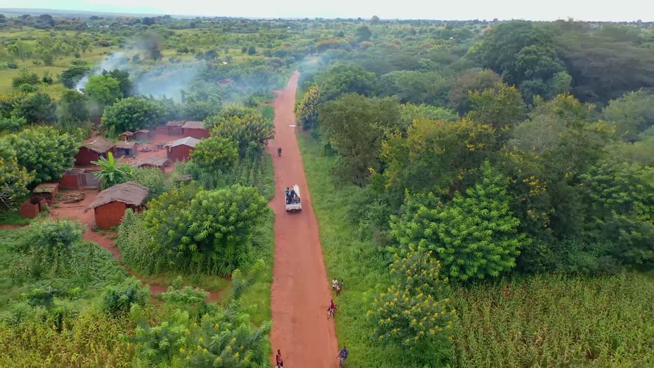 drone volando sobre un pueblo con un auto conduciendo hacia él