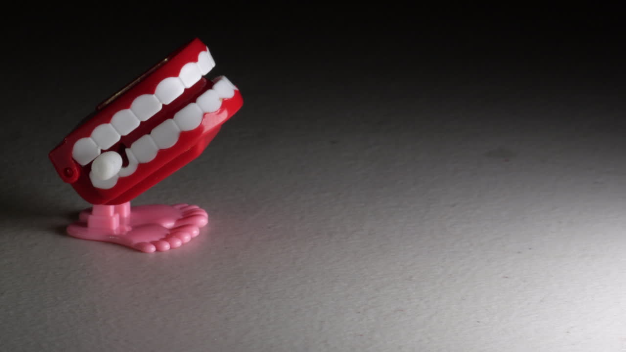 la mano masculina coloca un juguete novedoso que castañetea los dientes con pies cómicos