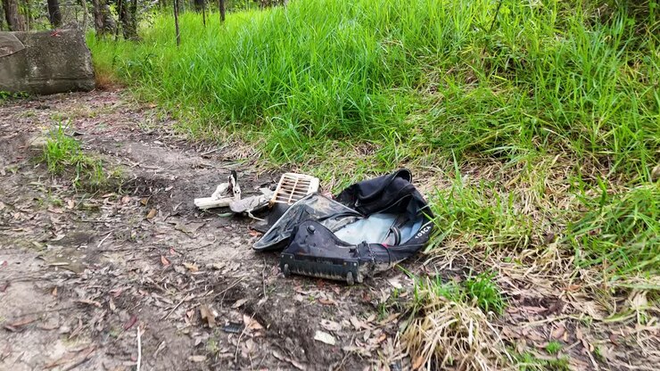 Discarded trash and debris litter a natural path on the Gold Coast, highlighting environmental pollution issues