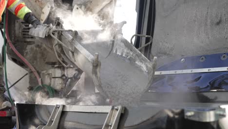concrete pouring process features medium shot of cement pouring down a chute, flowing into a construction site, with steam and dust rising from the wet concrete.