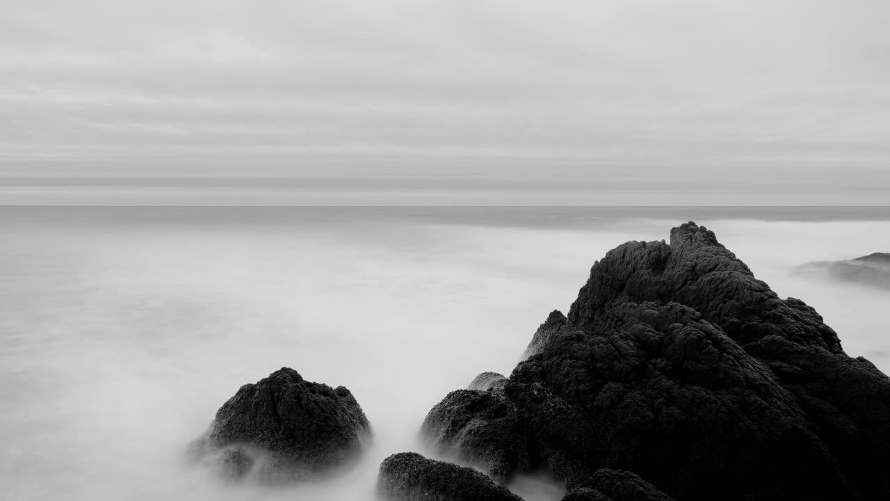 Bianco e nero drammatico con lunga esposizione di oceano e rocce