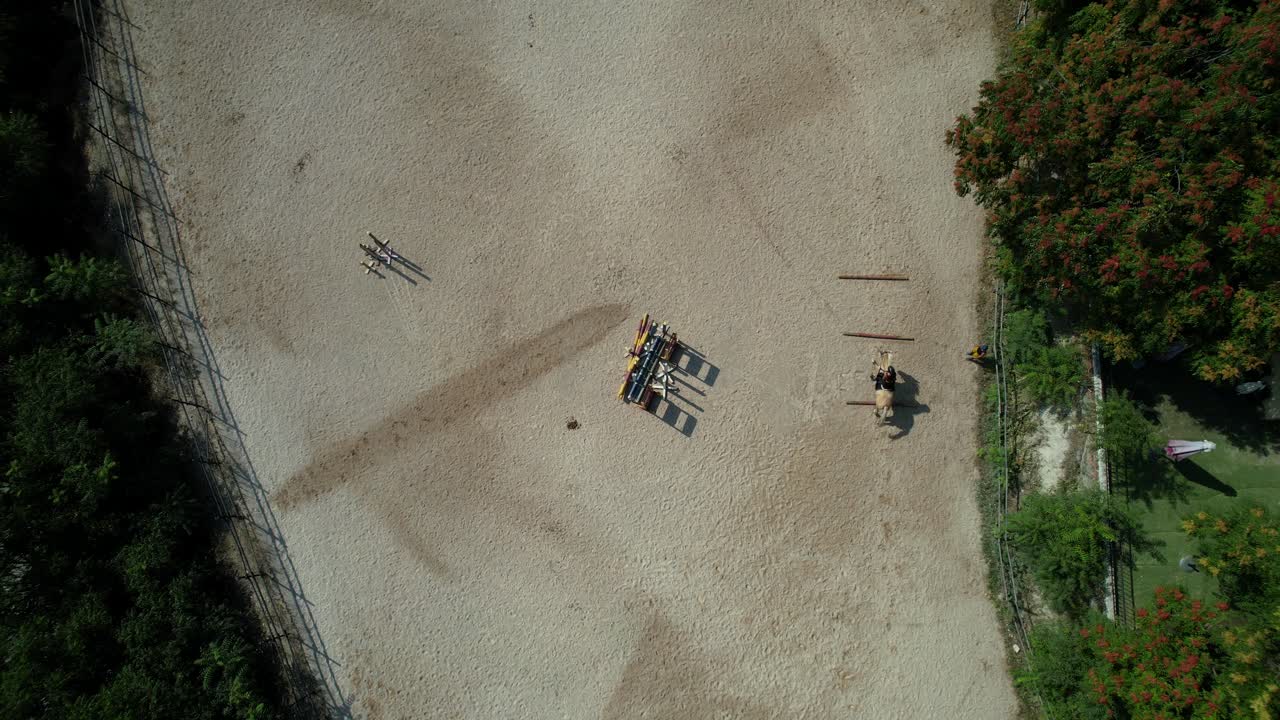 Top down descent shows two riders galloping around the track and jumping between bars in succession