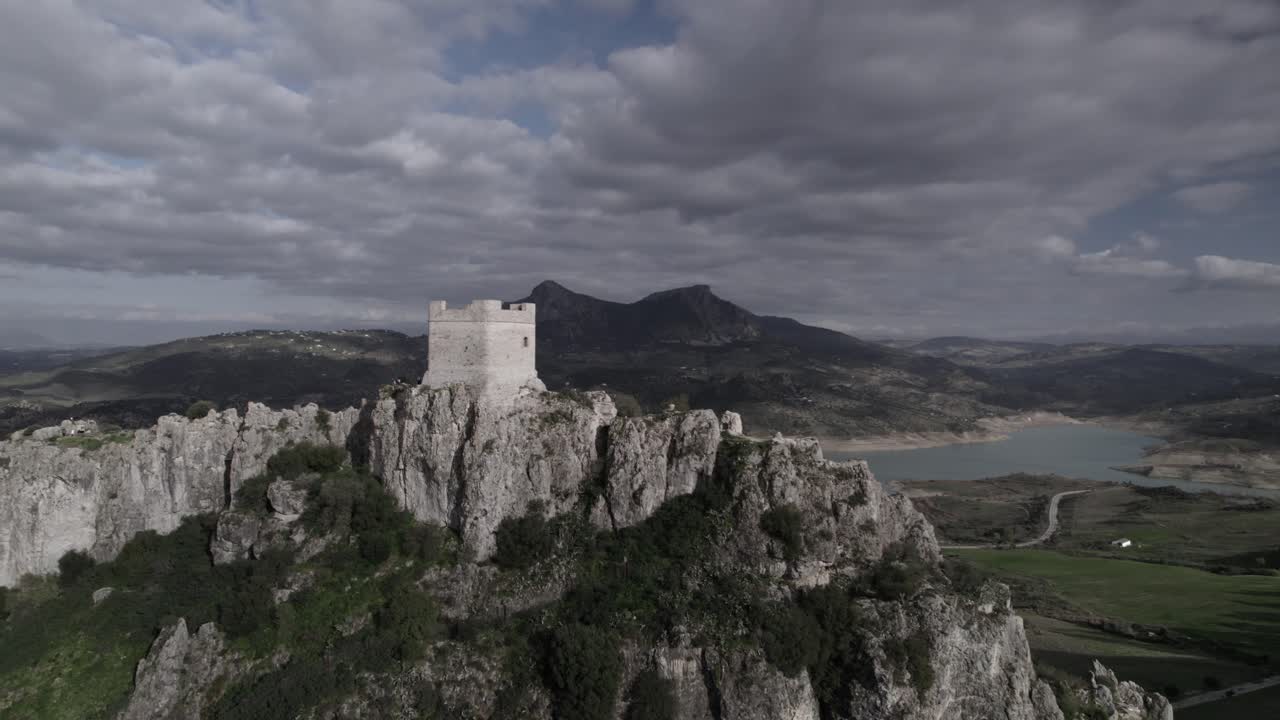 4K drone shot of Zahara de la Sierra, Spain, filmed with a DJI at 30fps. A cinematic backward flight revealing the medieval castle, the stunning reservoir, and the village below.