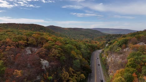 An-aerial-view-high-over-the-mountains-in-upstate-NY-during-the-fall-foliage-change,-on-a-beautiful-day-with-white-clouds