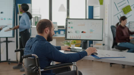 Businessman-with-disabilities-asking-information-to-woman-worker-typing-on-pc