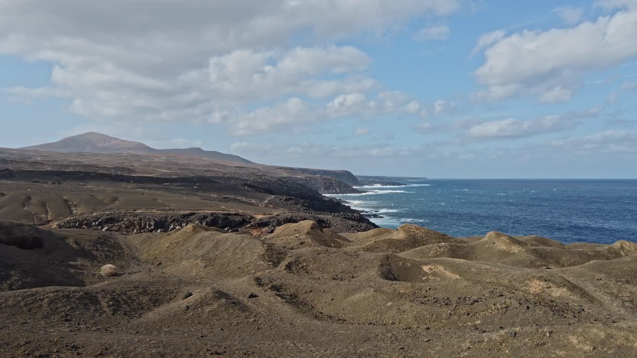 Volcanic landscape of lanzarote revealing dramatic interaction between rugged coastline and powerful ocean waves, showcasing raw natural beauty of canary islands seascape under bright summer sky