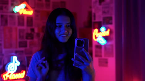 teenage girl using smartphone in neon lit room