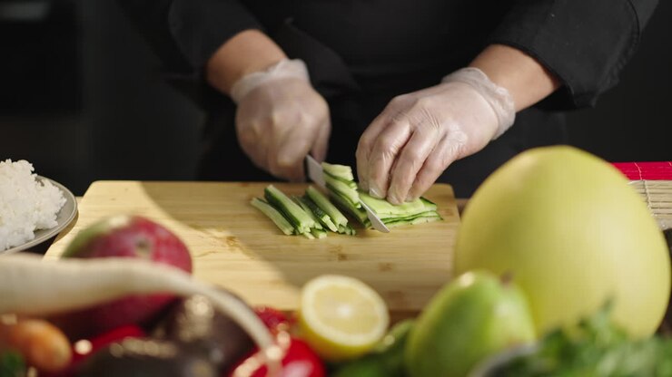 Chef Slicing Cucumbers on a Cutting Board