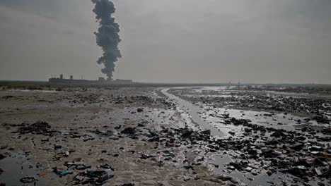 industrial plant emitting dark smoke into the atmosphere, polluting the surrounding landscape with garbage and debris, highlighting environmental damage and industrial pollution