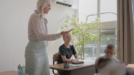 the teacher high-fives the boy in the classroom during the lesson. the teacher gives a high five to a girl in the classroom during the lesson. go through the class and give a high five