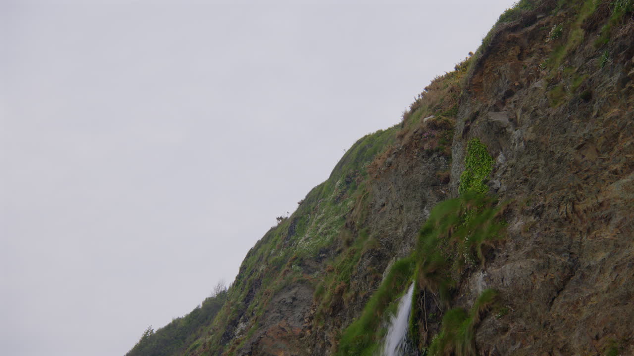 Tilting down mid shot of Tresaith waterfall