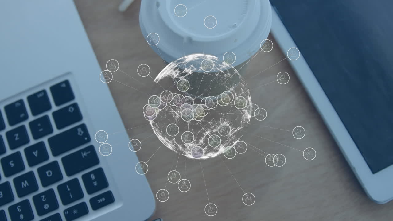 animación de un globo de iconos digitales contra una computadora portátil, una tableta digital y una taza de café en una mesa de madera