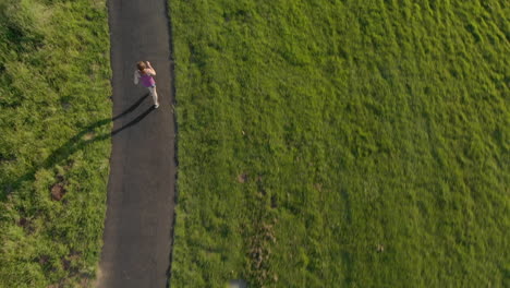 aerial of young woman running on a track at sunset