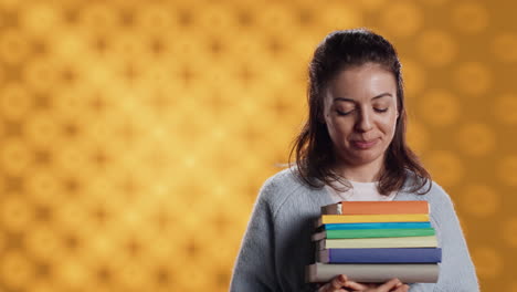 Portrait-of-happy-woman-with-stack-of-books-in-hands-showing-thumbs-up