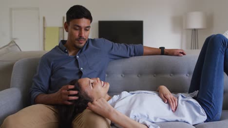 Romantic-hispanic-couple-cuddling-on-sofa-in-living-room