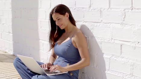 Smiling-young-woman-typing-on-her-laptop