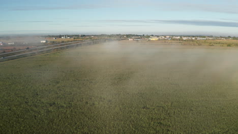 green farm fields on outskirts of rural town with road and traffic heading toward city