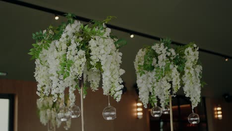 elegant hanging floral arrangements with white blossoms and glass globes, creating a luxurious event decor