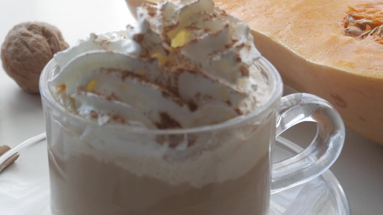 Paneo a la derecha hacia una taza de cristal transparente con café o cacao, crema, canela, calabaza, nueces y clavo. Sabores navideños.