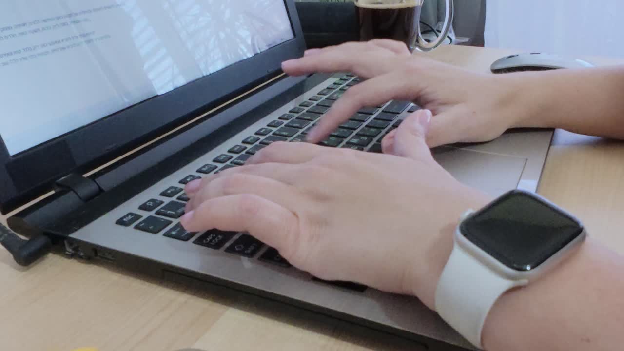 Starting the workday: hands typing on laptop, accompanied by morning coffee and smartwatch.
