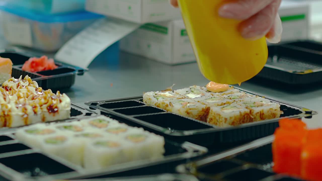 el cocinero agrega salsa a los rollos japoneses con anguila asada