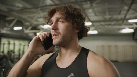 athletic man in sportswear talking on mobile phone in gym