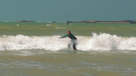 新手衝浪少女從衝浪板上墜落到海浪中,摩洛哥,埃薩奧尤拉