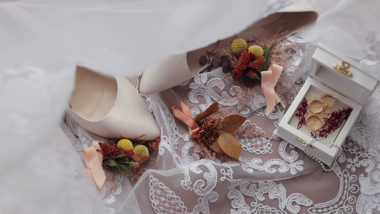 Wedding rings, flowers bouquet and bridal shoes, accessories for bride on window sill with curtains