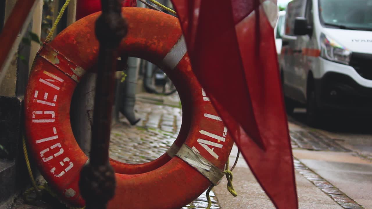 Close-up view through a Life Buoy of the street and sidewalk, Copenhagen, Denmark. Red flag waving in front of a life buoy.