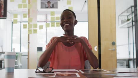 Smiling-african-american-businesswoman-at-desk-talking-and-gesturing-during-video-call-in-office