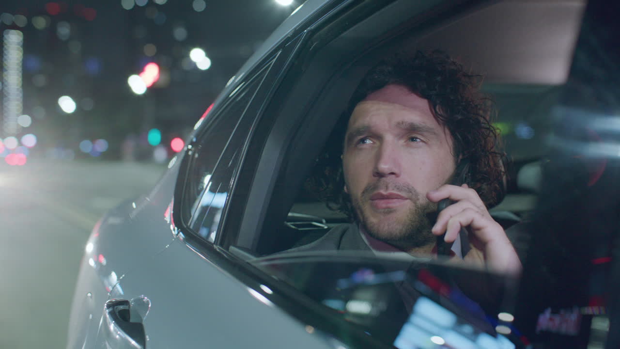 Businessman Looking through Car Window during Phone Conversation