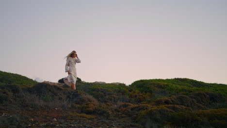 stylish woman exploring landscape alone vertical. blonde girl walking at sunset