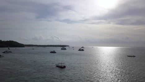 Wonderful-aerial-view-flight-slider-fly-sideways-from-left-to-right-drone-footage-over-the-bay-and-the-sun-mirroring-in-crystal-clear-water-at-Bali