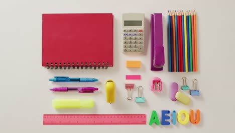 Video-of-composition-of-school-items-with-notebook-and-calculator-on-white-background