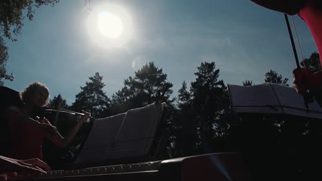 Joven-Violinista-Bonita-Tocando-El-Violín-Como-Parte-De-Un-Grupo-Contra-El-Fondo-Del-Cielo-En-Cámara-Lenta