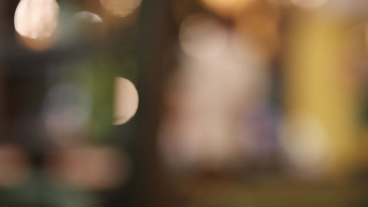 Tenui luci bokeh dorate brillano in un ambiente interno sfocato con illuminazione ambientale calda