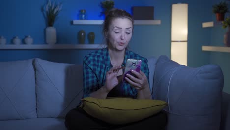 Woman-using-social-media-on-phone-laughing-at-night-at-home.