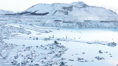 couple looking at magical colored water of blue lagoon in iceland, aerial