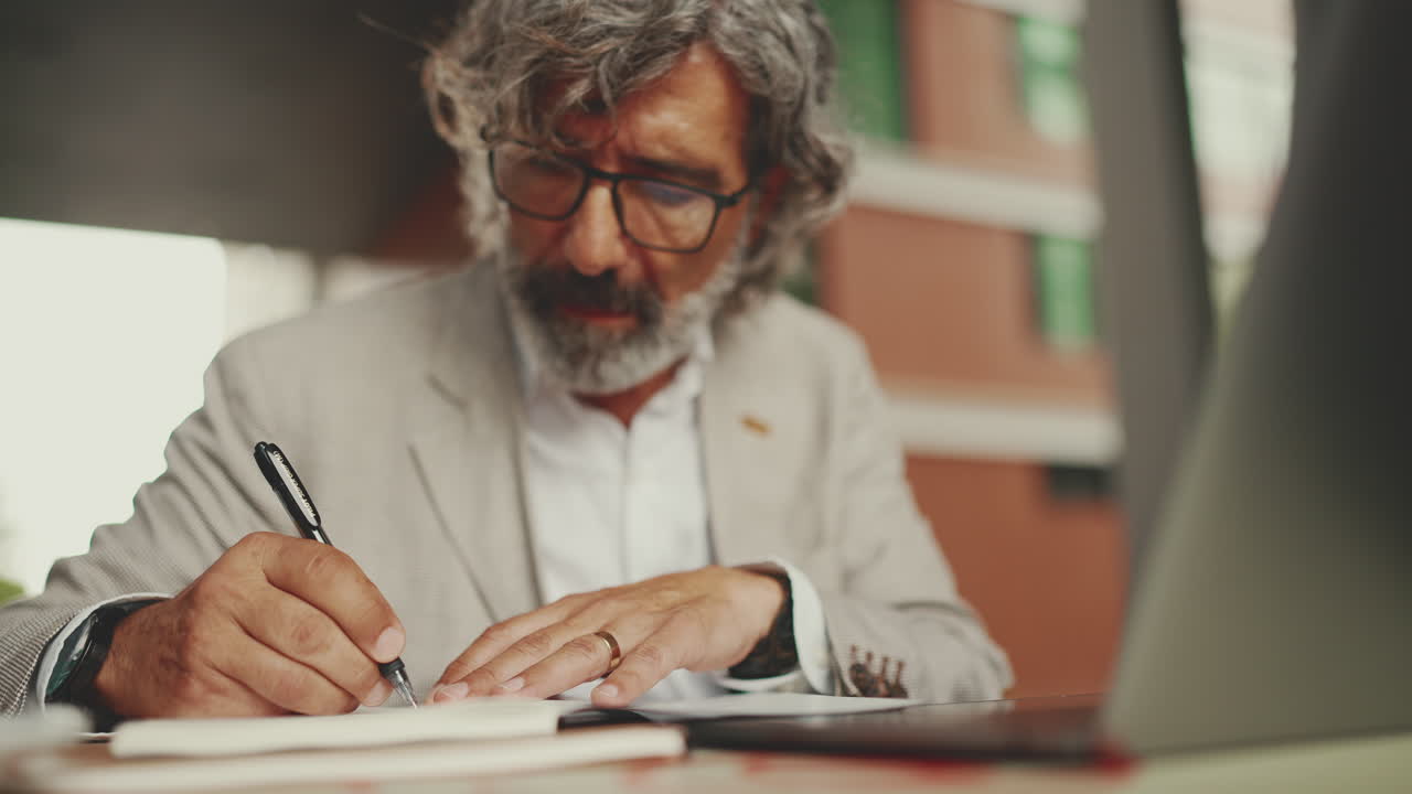 Senior man working with laptop and taking notes