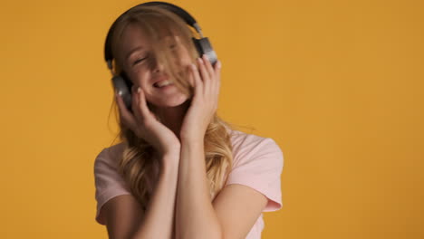 una mujer caucásica con auriculares escuchando música.