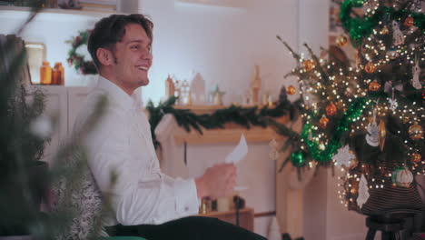 Hombre-Feliz-Leyendo-Una-Carta-En-Una-Casa-Decorada-Durante-La-Navidad