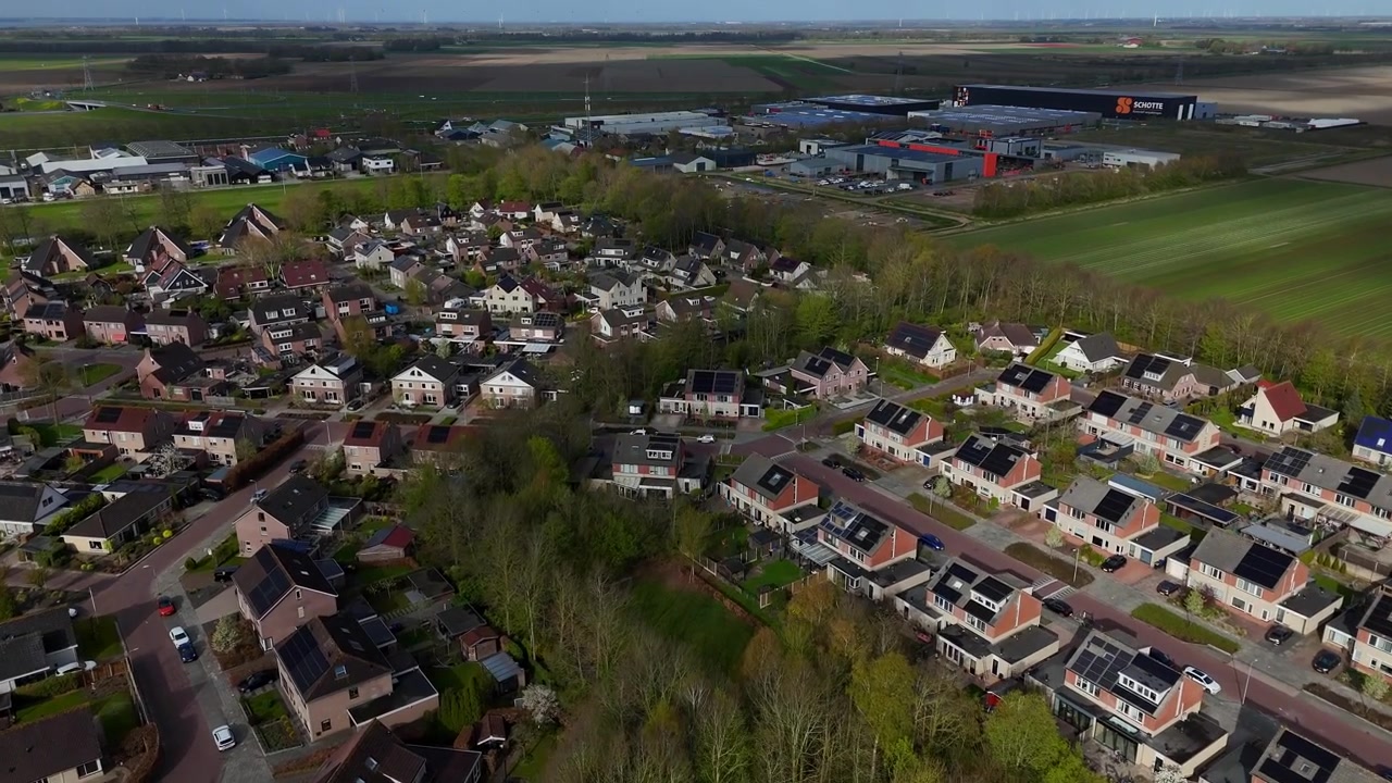 Dronebeelden van het Nederlandse dorp Ens, Noordoostpolder, Flevoland, Nederland. Overvlucht op hogere hoogte met industriegebied op de achtergrond.