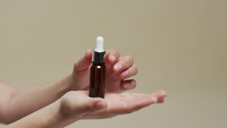 manos de una mujer sosteniendo un frasco con cosméticos en fondo beige con espacio para copiar, cámara lenta