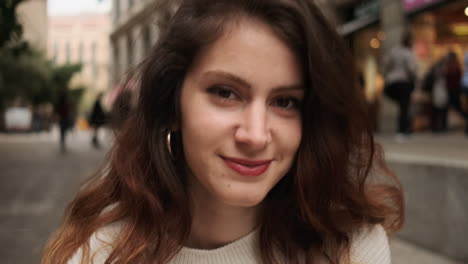 smiling girl looking at camera while holds cellphone